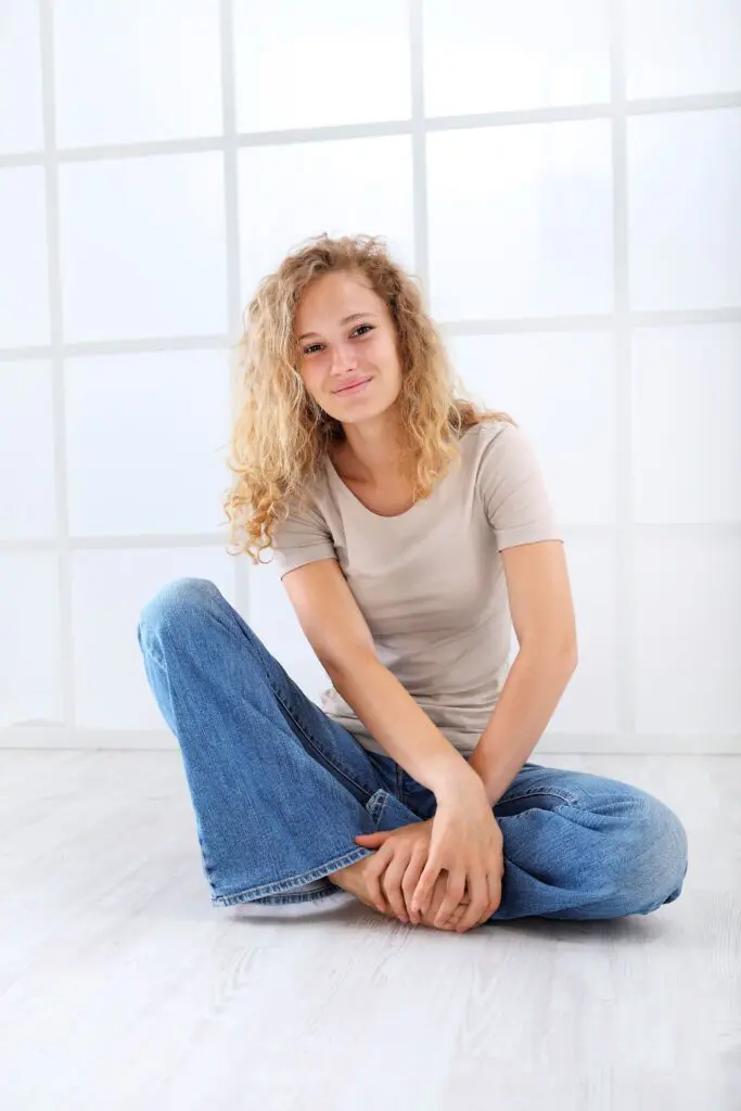Vaginalgeruch: Frau sitzt lächelnd auf dem Boden.