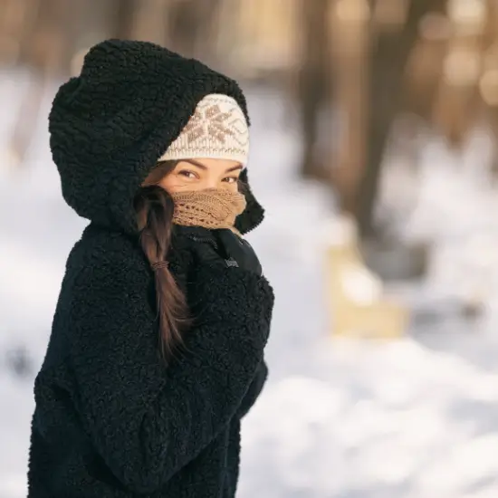 Um sich vor Erfrierungen zu schützen, ist eine Frau im Winter in warme Klamotten gepackt.