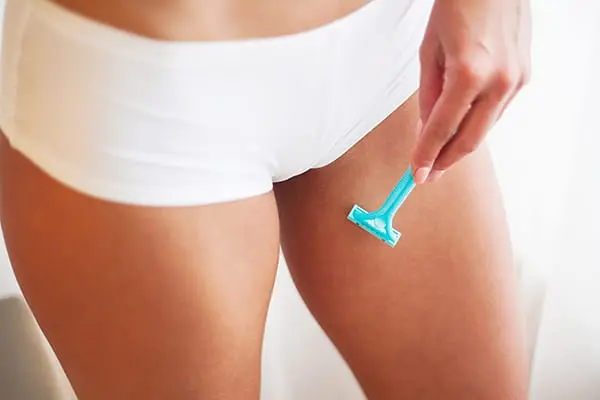 Zur richtigen Intimhygiene gehört auch die Intimrasur: Frau hält Rasierer in den Intimbereich.