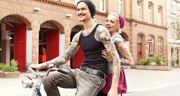 Optimale Pflege von Tattoos: Tätowiertes Paar auf einem Fahrrad.